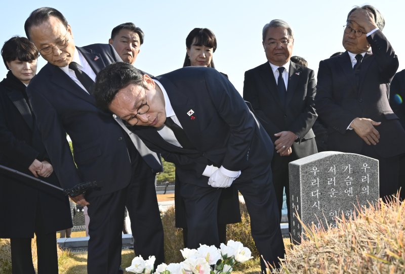 [광주=뉴시스] 박기웅 기자 = 김민석 국무총리가 26일 오후 광주 북구 운정동 국립5·18민주묘지를 방문해 문재학 열사 묘 앞에서 참배한 뒤 묘비를 살펴보고 있다. 이날 참배를 마친 김 총리는 기아 오토랜드 광주공장을 시찰, 동천동 골목상권과 1913송정역시장 등을 방문한다. 2025.11.26. pboxer@newsis.com