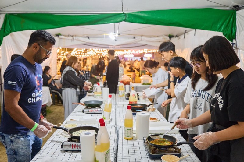 '2025 별바다부산 나이트 페스타' 나이트 마켓 현장에서 국내외 관광객들이 찌짐(전) 만들기 체험을 하고 있는 모습.