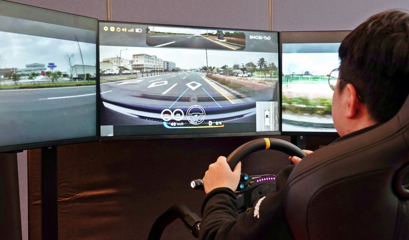 [제주=뉴시스] 오영재 기자 = 27일 오후 제주시 쏘카터미널에서 열린 원격 운전 실증 성과 공유회에서 관계자가 원격 조종을 통해 차량을 실제로 운전하고 있다. 2025.11.27. oyj4343@newsis.com