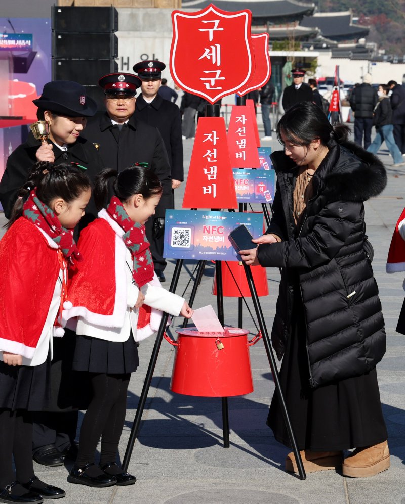 [서울=뉴시스] 추상철 기자 = 28일 오전 서울 종로구 광화문광장에서 열린 '2025 구세군 자선냄비 시종식'에서 서울 주니어 합창단 어린이와 학부모가 현금 및 NFC 자선냄비 모금 시연을 하고 있다. 2025.11.28. scchoo@newsis.com