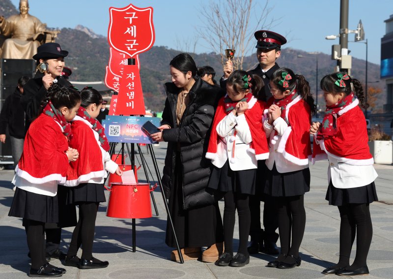 [서울=뉴시스] 추상철 기자 = 28일 오전 서울 종로구 광화문광장에서 열린 '2025 구세군 자선냄비 시종식'에서 서울 주니어 합창단 어린이와 학부모가 현금 및 NFC 자선냄비 모금 시연을 하고 있다. 2025.11.28. scchoo@newsis.com