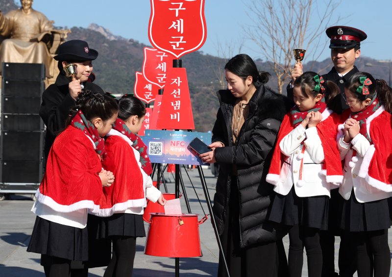 [서울=뉴시스] 추상철 기자 = 28일 오전 서울 종로구 광화문광장에서 열린 '2025 구세군 자선냄비 시종식'에서 서울 주니어 합창단 어린이와 학부모가 현금 및 NFC 자선냄비 모금 시연을 하고 있다. 2025.11.28. scchoo@newsis.com