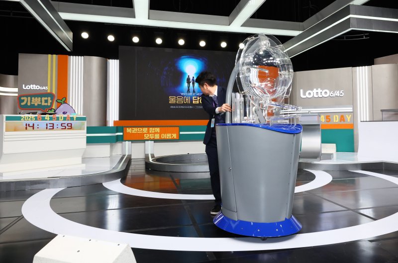 [서울=뉴시스] 황준선 기자 = 29일 오후 서울 마포구 MBC 경영센터 내 스튜디오에서 관계자들이 대국민 로또 6/45 추첨 공개방송 '645 데이'를 위해 추첨 장비를 옮기고 있다. 로또복권 추첨 과정의 공정성과 투명성을 알리기 위해 기획재정부 복권위원회 동행복권이 초청한 참관인 100명은 이날 추첨기 점검과 리허설, 추첨 생방송 등 추첨 절차의 전 과정을 참관한다. 2025.11.29. hwang@newsis.com