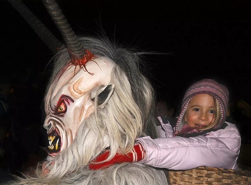크람푸스 분장을 한 어른에게 엎힌 아이가 활짝 웃음 짓고 있다.(오스트리아관광청 제공)