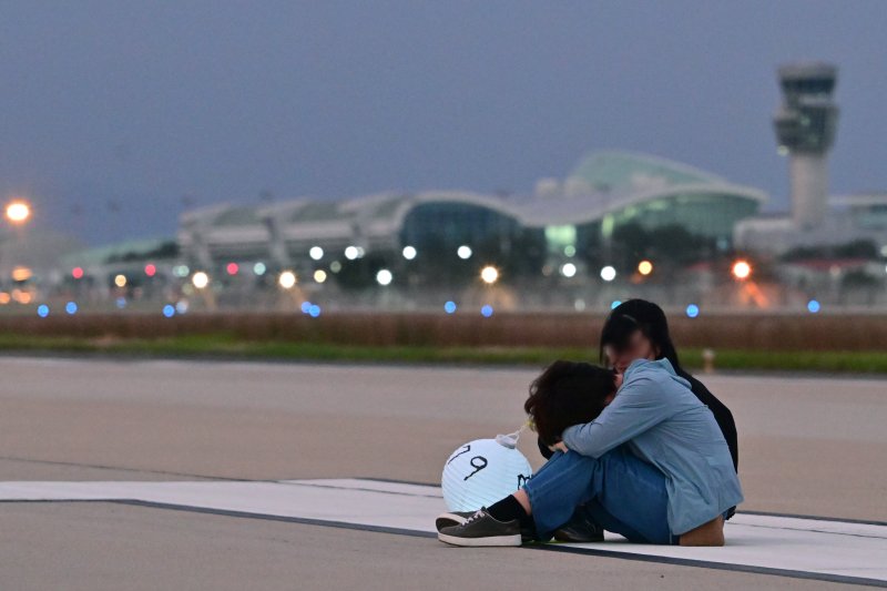 [무안=뉴시스] 이영주 기자 = 추석 당일인 6일 오후 전남 무안군 무안국제공항 활주로에서 12·29 무안공항 제주항공 여객기 참사 유가족협의회가 참사 희생자들의 넋을 위로하며 '기억의 활주로, 별이 된 당신께' 유등행사를 진행하고 있다. 행사 진행 도중 한 유족이 주저앉아 절규하고 있다. 2025.10.06. leeyj2578@newsis.com