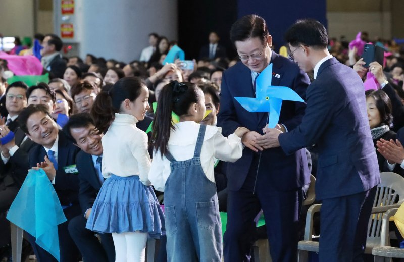 [고양=뉴시스] 최동준 기자 = 이재명 대통령이 2일 경기 고양시 킨텍스에서 열린 제22기 민주평화통일자문회의 출범회의에서 '함께하는 다짐, 함께 부르는 평화' 대합창을 하며 어린이들로부터 바람개비를 전달 받고 있다. 2025.12.02. photocdj@newsis.com