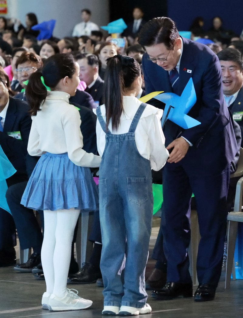 [고양=뉴시스] 최동준 기자 = 이재명 대통령이 2일 경기 고양시 킨텍스에서 열린 제22기 민주평화통일자문회의 출범회의에서 '함께하는 다짐, 함께 부르는 평화' 대합창을 하며 어린이들로부터 바람개비를 전달 받고 있다. 2025.12.02. photocdj@newsis.com