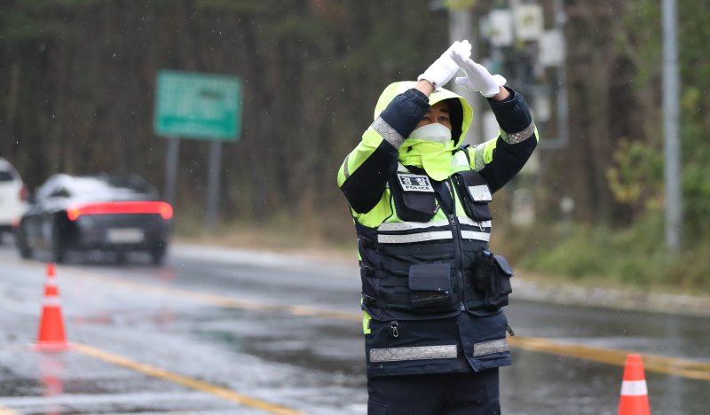 [제주=뉴시스] 우장호 기자 = 제주 산간에 대설특보가 내려진 3일 오전 제주시 1100도로 초입부인 어승생 삼거리에서 제주서부경찰서 소속 경찰관이 운전자들에게 교통 통제 수신호를 보내고 있다. 2025.12.03. woo1223@newsis.com