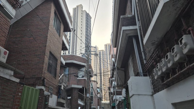 [서울=뉴시스] 정진형 기자 = 서울 광진구 자양동 자양1-4구역 가로주택정비사업 대상지의 골목 사이로 자양1구역 재건축으로 조성된 '롯데캐슬 리버파크 시그니처'가 보이고 있다. 2025.12.01. formation@newsis.com *재판매 및 DB 금지