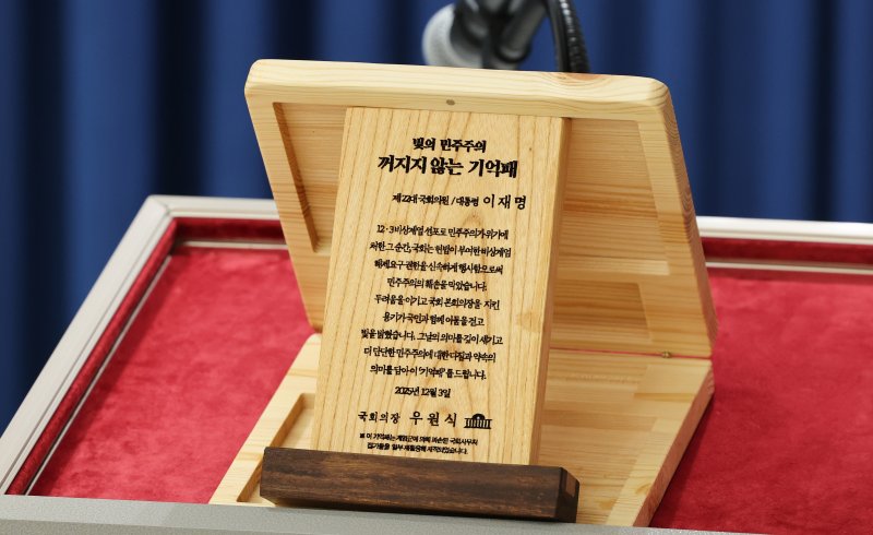 3일 서울 용산 대통령실 청사에서 열린 5부 요인 초청 오찬 관련 브리핑에서 '빛의 민주주의 꺼지지 않는 기억패'가 공개되고 있다. 이재명 대통령은 이날 오찬에서 우원식 국회의장으로부터 지난해 12월 3일 계엄군에 의해 부서졌던 국회 집기들을 재활용해 만든 '기억패'를 전달 받았다. 2025.12.3/뉴스1 ⓒ News1 허경 기자