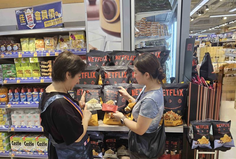 GS25 직원들이 홍콩 파크앤샵에 진출한 넷플릭스 지식재산권(IP) 제휴 상품을 손에 들고 있다. GS리테일 제공