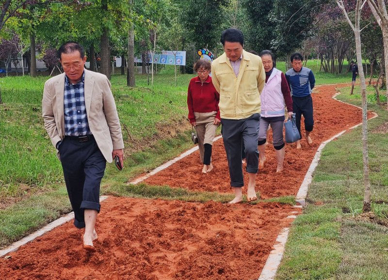 [광주=뉴시스] 광주 광산구가 주민참여예산 사업으로 평동 옥동1근린공원에 조성한 '평동 맨발길'에서 주민들이 맨발 걷기를 하고 있다. (사진 = 광주 광산구 제공) 2025.10.22. photo@newsis.com *재판매 및 DB 금지