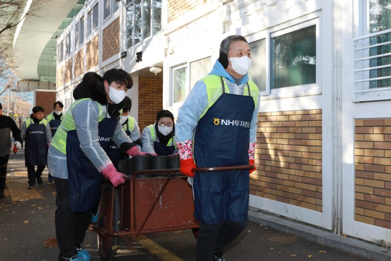 윤병운 NH투자증권 대표이사(앞줄 오른쪽)가 지난 3일 서울 영등포구 쪽방촌에서 임직원과 연탄을 나르고 있다. NH투자증권 제공