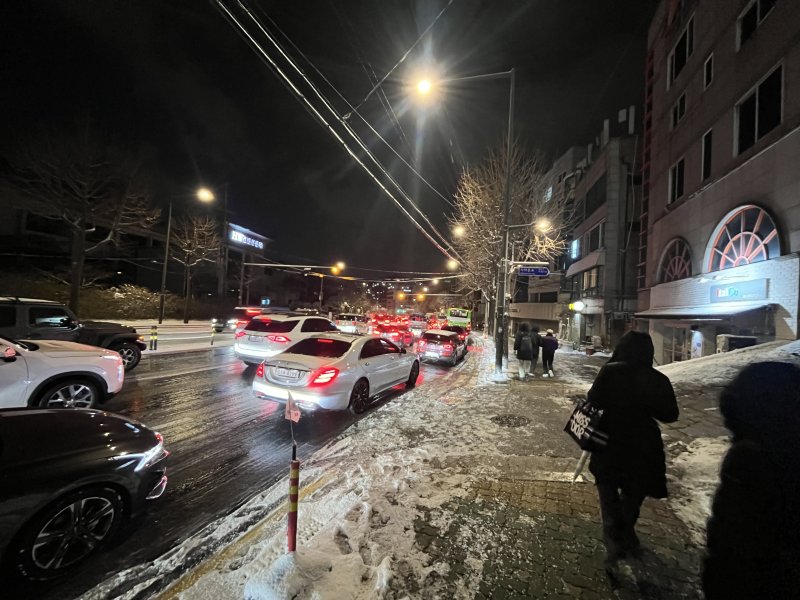 폭설이 내린 4일 오후 서울 종로구 자하문로에서 차량들이 눈길에 큰 정체를 빚자 시민들이 버스에서 내려 걸어가고 있다.2025.12.4/뉴스1 ⓒ News1 황기선 기자