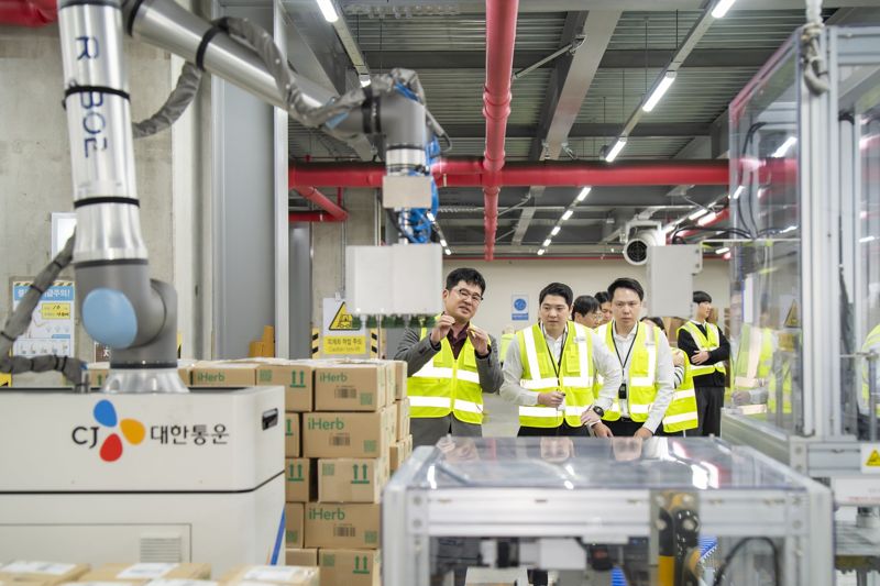 CJ대한통운 인천 GDC를 방문한 태국 최대 유통사 CP 엑스트라 경영진들이 박스를 자동 분류해 파렛트에 쌓는 '이동형 로봇 팔레타이저'에 대해 설명을 듣고 있다.