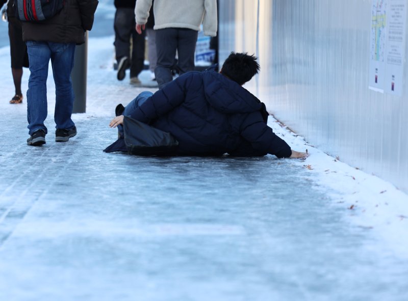 폭설 후 한파로 도로 곳곳이 얼어붙은 5일 오전 서울 광화문역 일대에서 한 시민이 빙판길에 미끄러져 넘어지고 있다. 2025.12.5/뉴스1 ⓒ News1 구윤성 기자