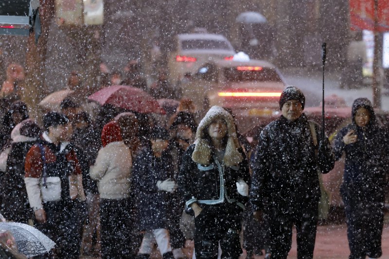 첫눈이 내린 4일 오후 서울 중구 명동을 찾은 관광객들이 내리는 눈을 맞으며 즐거워하고 있다. 기상청은 "퇴근 시간대 강한 눈이 내릴 가능성이 크다＂며 동네 예보와 실시간 날씨를 확인할 것을 당부했다. 뉴스1