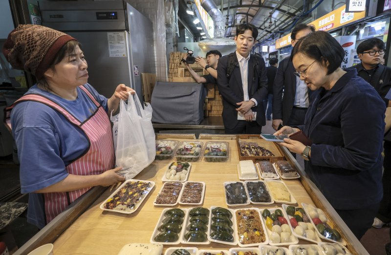 [서울=뉴시스] 정병혁 기자 = 한성숙 중소벤처기업부 장관이 지난 10월 1일 서울 서대문구 영천시장을 찾아 떡을 구매하고 있다. 2025.12.05 jhope@newsis.com