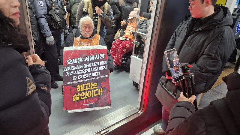 [서울=뉴시스] 전상우 수습기자 = 박경석 전국장애인차별철폐연대(전장연) 상임공동대표가 5일 오전 서울 지하철 4호선 혜화역 열차 안에서 장애등급제 폐지와 권리중심일자리 최중증장애인노동자 해고 철회를 촉구하며 선전전을 벌이고 있다. 2025.12.05. swoo@newsis.com