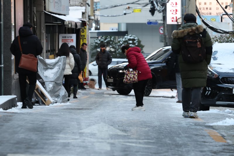 [서울=뉴시스] 권창회 기자 = 폭설 후 한파로 도로 곳곳이 얼어붙은 5일 오전 서울 중구 충무로역 인근에서 시민들이 빙판길을 조심히 걷고 있다. 2025.12.05. kch0523@newsis.com