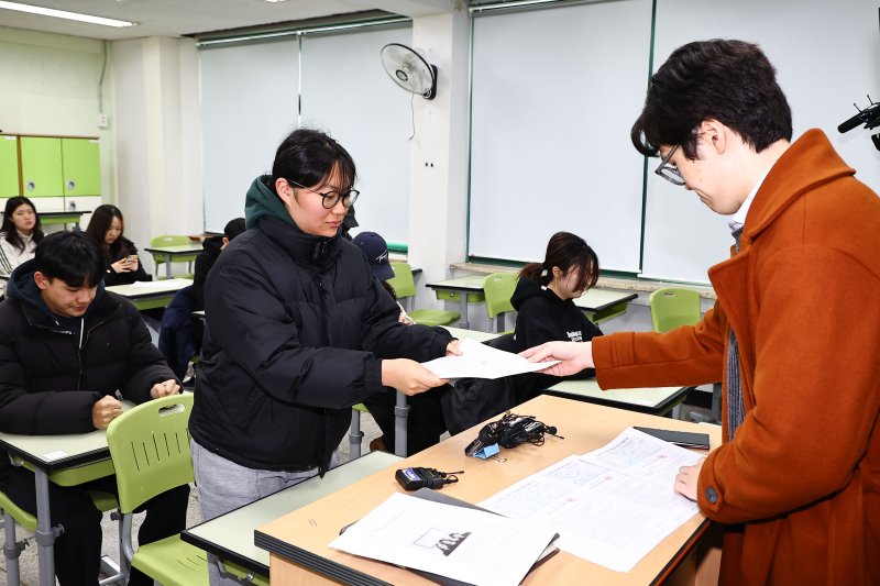 [서울=뉴시스] 홍효식 기자 = 2026학년도 대학수학능력시험(수능) 성적표가 배부된 5일 서울 광진구 광남고등학교에서 담임선생님이 수험생에게 성적표를 배부하고 있다. (공동취재) 2025.12.05. photo@newsis.com