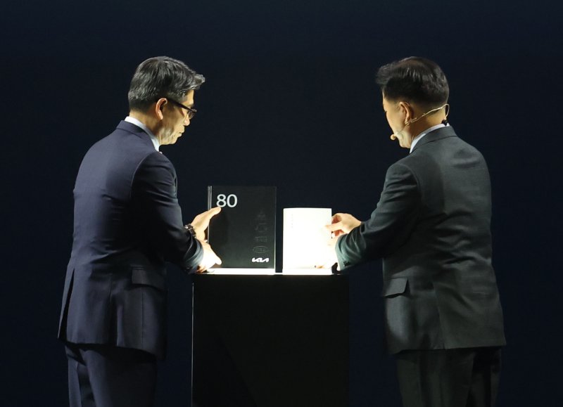 송호성 기아 대표이사 사장과 정의철 기아 기업전략실 전무가 5일 경기 용인시 처인구 기아 비전스퀘어에서 열린 '기아 80주년 기념식'에서 기아 80년 사사를 공개하고 있다. 2025.12.5/뉴스1 ⓒ News1 김영운 기자