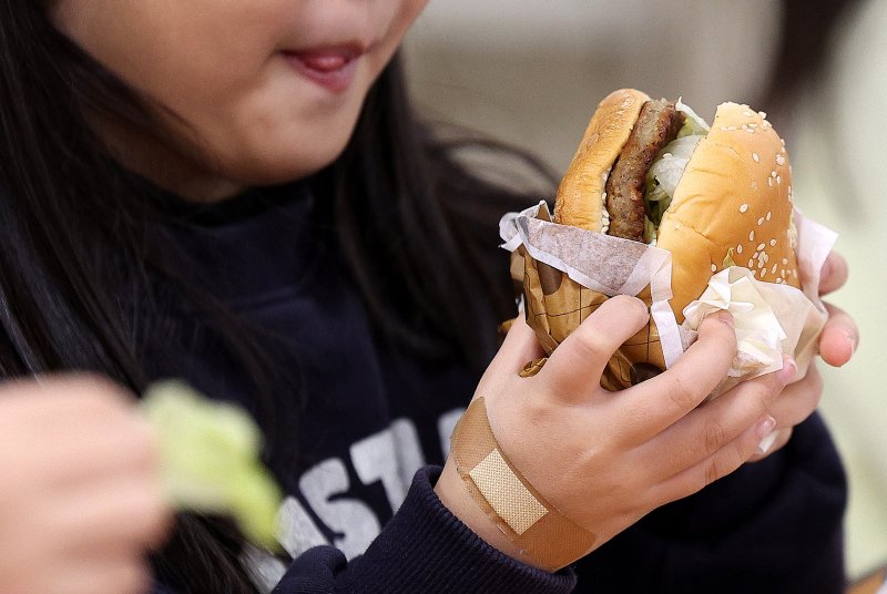 [대구=뉴시스] 이무열 기자 = 전국학교비정규직연대회의의 파업에 따라 대구지역 일부 학교에서 대체식이 제공된 5일 대구 한 초등학교 급식실에서 학생들이 대체식으로 햄버거를 먹고 있다. 2025.12.05. lmy@newsis.com