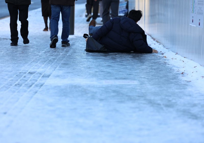 폭설 후 한파로 도로 곳곳이 얼어붙은 5일 오전 서울 광화문역 일대에서 한 시민이 빙판길에 미끄러져 넘어지고 있다. 2025.12.5/뉴스1 ⓒ News1 구윤성 기자