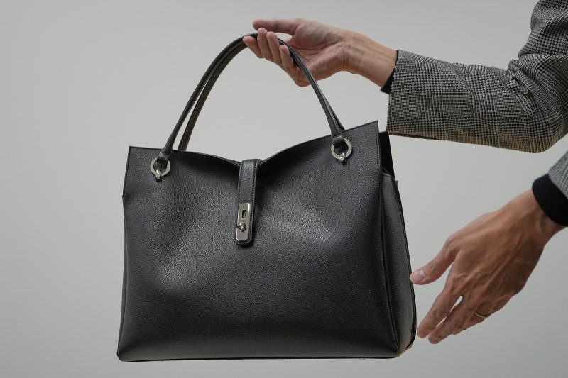 [도쿄=AP/뉴시스] 일본 '하마노 피혁공예'의 홍보 담당자가 지난 2일 도쿄에서 다카이치 사나에 총리가 사용하는 토트백 모델을 들어보이는 모습.