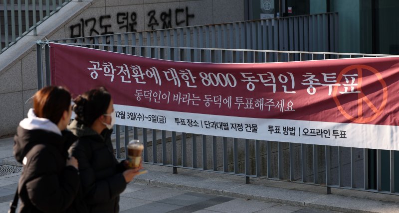 [서울=뉴시스] 홍효식 기자 = 동덕여자대학교 공학 전환 타당성에 대한 외부 용역 결과 발표와 '공학 전환에 대한 8000 동덕인 의견 조사' 학생 총투표가 실시되는 3일 서울 성북구 동덕여대에서 학생들이 총투표 관련 현수막 앞을 지나가고 있다. 2025.12.03. yesphoto@newsis.com