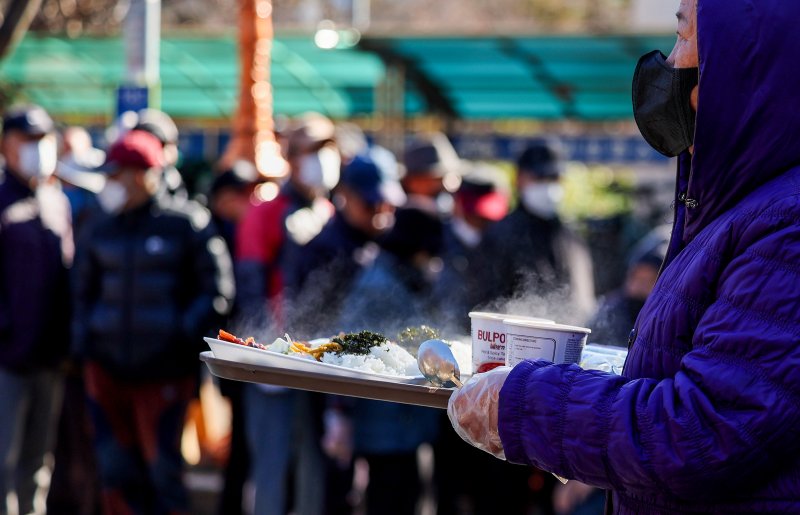 [대구=뉴시스] 이무열 기자 = 쌀쌀한 날씨를 보인 9일 대구 달서구 두류공원 사랑해밥차 무료 급식소에서 한 어르신이 배식 받은 점심을 들고 이동하고 있다. 2025.12.09. lmy@newsis.com