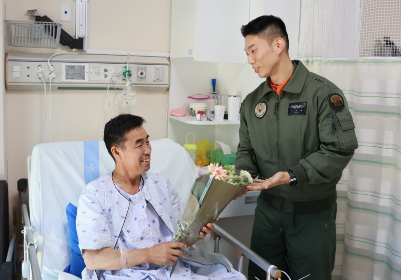 육군은 지난 1일 육군 3군단 직할 항공단 소속 이지홍 대위가 공사 중 차량사고로 생명이 위급한 민간인을 응급조치하고 신속한 판단으로 군 의무후송헬기(메디온)으로 이송해 소중한 생명을 구했다고 10일 밝혔다. 이지홍 대위가 국군수도병원에 방문해 박병춘 씨 병문안하고 있다. 육군 제공