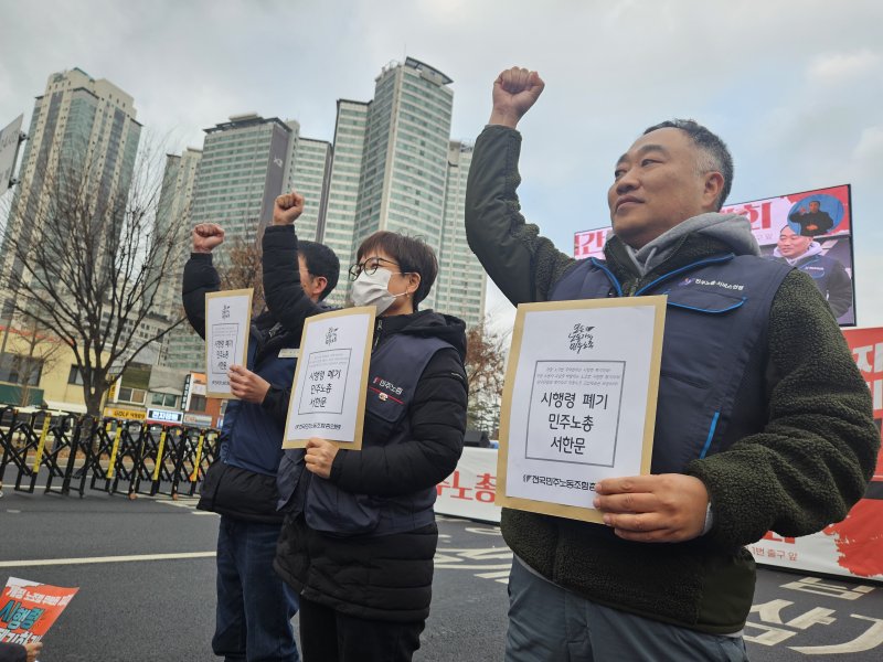 10일 오후 서울 용산구 삼각지역 인근에서 진행된 전국민주노동조합총연맹 결의대회에서 참가자 3명이 대통령실에 전달할 '시행령 폐기 민주노총 서한문'을 들어보이고 있다. 2025.12.10/뉴스1 ⓒ News1 유채연 기자