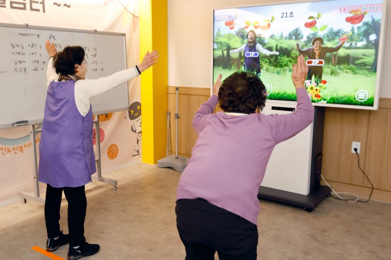 [수원=뉴시스] 인공지능(AI) 사랑방에서 화면에 나오는 자신의 모습을 보고 게임을 즐기는 어르신들. (사진=경기도 제공) 2025.12.11. photo@newsis.com *재판매 및 DB 금지