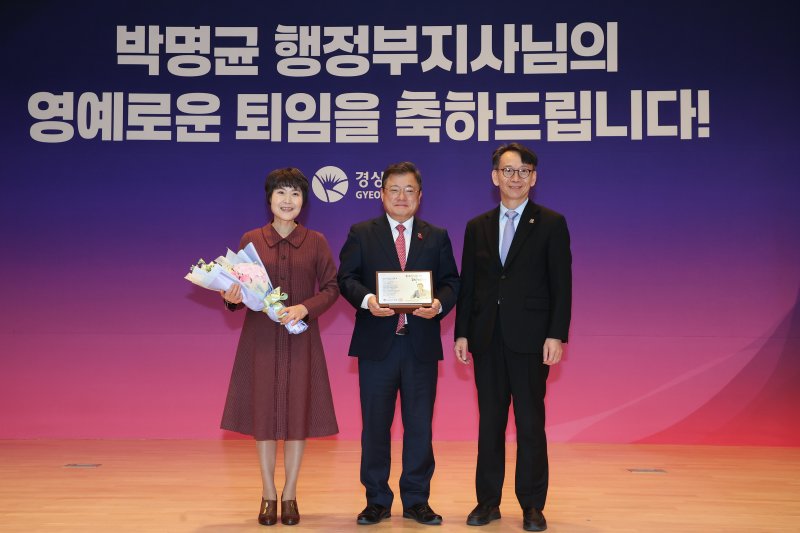 [창원=뉴시스]박명균(가운데) 경남도 행정부지사가 11일 도청 본관 대회의실에서 퇴임식을 갖고 김명주 경제부지사로부터 퇴임 기념패를 받은 후 기념촬영하고 있다.(사진=경남도 제공) 2025.12.11. photo@newsis.com