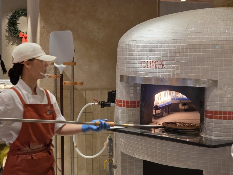CJ푸드빌이 11일 새 외식 브랜드 올리페페를 오픈했다. 직원이 화덕에서 피자를 굽고 있다. ⓒ News1 이형진 기자