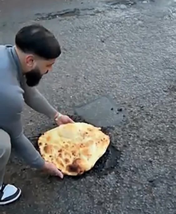[서울=뉴시스]영국의 한 인도 음식점 사장이 직접 구운 난으로 도로를 정비하고 있다. (사진 = 더 선 캡처)