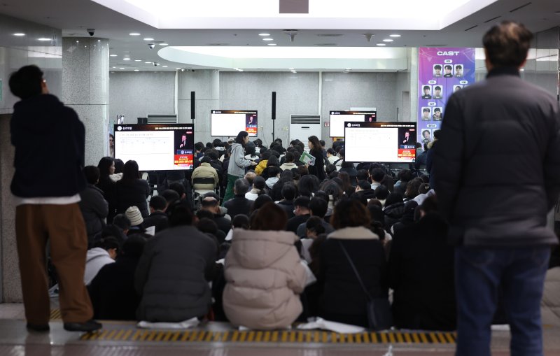 [서울=뉴시스] 김진아 기자 =지난 7일 서울 종로구 성균관대학교 600주년 기념관에서 열린 종로학원 주최 2026 정시 합격 가능선 예측 및 지원전략 설명회에 들어가지 못한 참석자들이 복도에서 설명회를 듣고 있는 모습. 2025.12.07. bluesoda@newsis.com