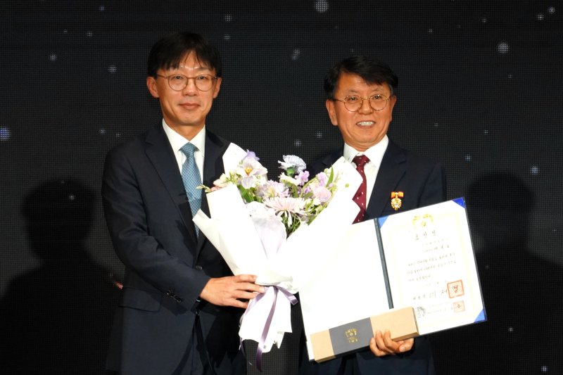 [창원=뉴시스]DN솔루션즈 배규호(오른쪽) 수석부사장이 제25회 공작기계인의 날 기념 행사에서 대통령 표창을 수상한 후 념촬영하고 있다.(사진=DN솔루션즈 제공) 2025.12.14. photo@newsis.com