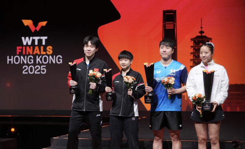 [홍콩=신화/뉴시스] 임종훈과 신유빈(오른쪽)이 13일(현지 시간) 중국 홍콩에서 열린 2025 월드테이블테니스(WTT) 홍콩 파이널스 혼합 복식 정상에 올라 시상대에서 트로피를 들고 포즈를 취하고 있다. 임종훈-신유빈 조는 결승에서 왕추친-쑨잉사 조(중국)를 3-0(11-9 11-8 11-6)으로 완파하고 한국 선수로는 처음으로 우승을 차지했다. 2025.12.14.
