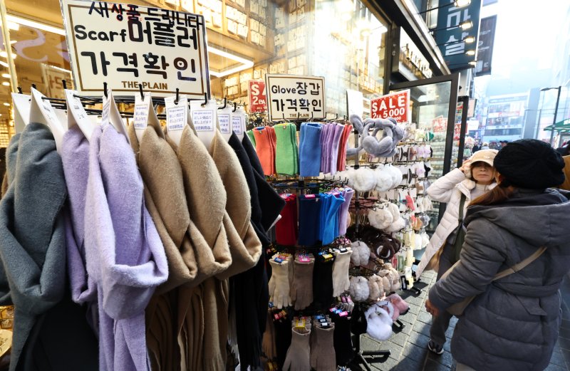 [서울=뉴시스] 최진석 기자 = 갑작스러운 강추위로 한파가 이어지고 있는 7일 서울 중구 명동에 한 상점에서 고객이 머플러와 장갑, 귀마개 등 방한용품을 고르고 있다. 2025.12.07. myjs@newsis.com
