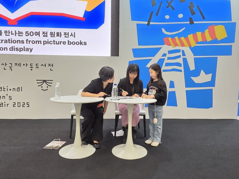 [부산=뉴시스] 조기용 기자 = 14일 부산 벡스코 제1전시장 3홀에서 열린 2025 부산국제아동도서전의 대담 '닻을 올리고 항해를 떠나는 여정'에 책 '빨간 사과가 먹고 싶다면'의 이가희·진주 작가가 참석했다. 대담 이후 어린이 독자를 만나 사인회를 진행했다. 2025.12.14. excuseme@newsis.com