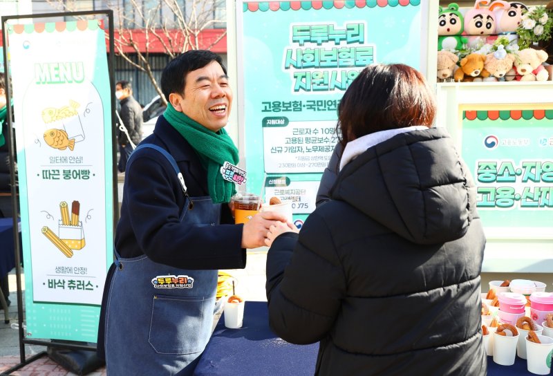박종길 근로복지공단 이사장(왼쪽)이 지난 12일 '두루누리·푸른씨앗 푸드트럭 이벤트' 현장에서 시민에게 커피와 간식을 나눠주고 있다. 근로복지공단 제공