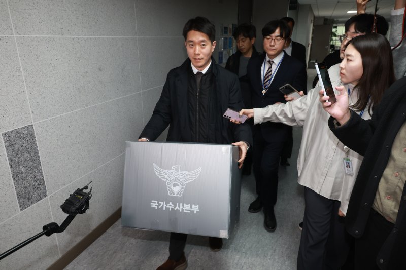 [서울=뉴시스] 고승민 기자 = 경찰이 통일교 관련 전방위적으로 압수수색에 나선 15일 서울 여의도 국회 의원회관 전재수 더불어민주당 의원실 압수수색을 마친 경찰 국가수사본부 관계자가 압수물품을 들고 건물을 나서고 있다. 2025.12.15. kkssmm99@newsis.com