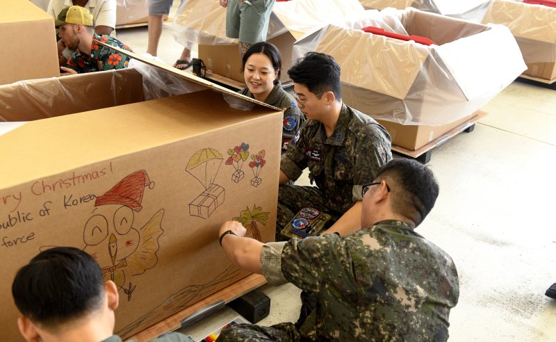 공군이 지난 7일부터 14일까지 괌 앤더슨 공군기지에서 미 태평양 공군사령부가 주관하는 인도적 지원 작전인 크리스마스 공수작전에 참가했다고 16일 밝혔다. 지난 6일 크리스마스 공수작전에 참가한 한측 요원들이 앤더슨 공군기지에서 진행된 '번들 빌드' 행사에서 투하 번들에 그림을 그리고 있다. 공군 제공