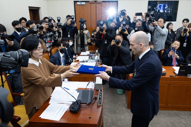 해롤드 로저스 쿠팡 임시 대표가 17일 서울 여의도 국회 과학기술정보방송통신위원회에서 열린 쿠팡 개인정보 유출 사고 관련 청문회에서 증인 선서를 마친 후 최민희 과방위원장에게 선서문을 전달하고 있다. 2025.12.17/뉴스1 ⓒ News1 유승관 기자
