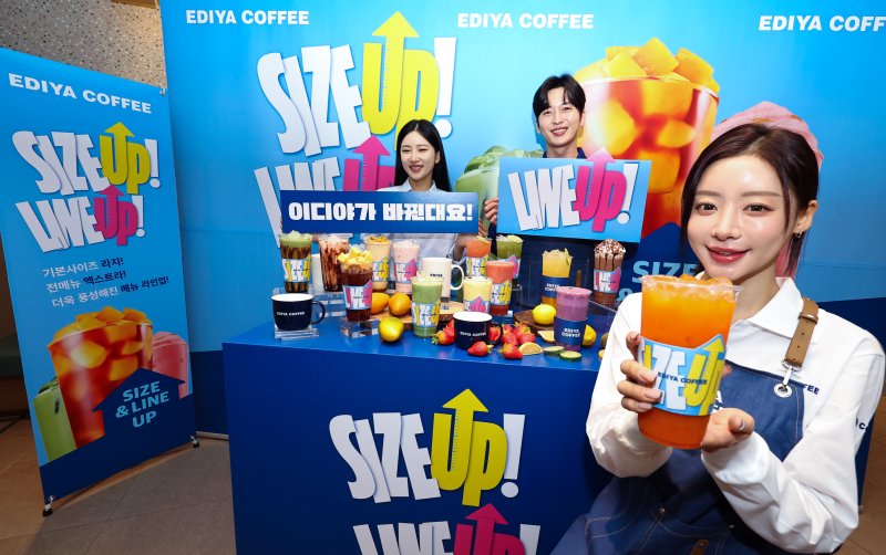 [서울=뉴시스] 최진석 기자 = 16일 서울 중구 한 이디야커피 매장에서 열린 음료 용량 확대 및 메뉴 라인업 개편을 알리는 'SIZE UP & LINE UP' 행사에서 모델이 행사를 사이즈업 잔을 들어 보이고 있다. 이디야커피는 음료 사이즈 체계를 라지와 엑스트라 기준으로 통일, 기존 14온스 중심의 운영 기준을 18온스 기반으로 정비했다. 2025.12.16. myjs@newsis.com