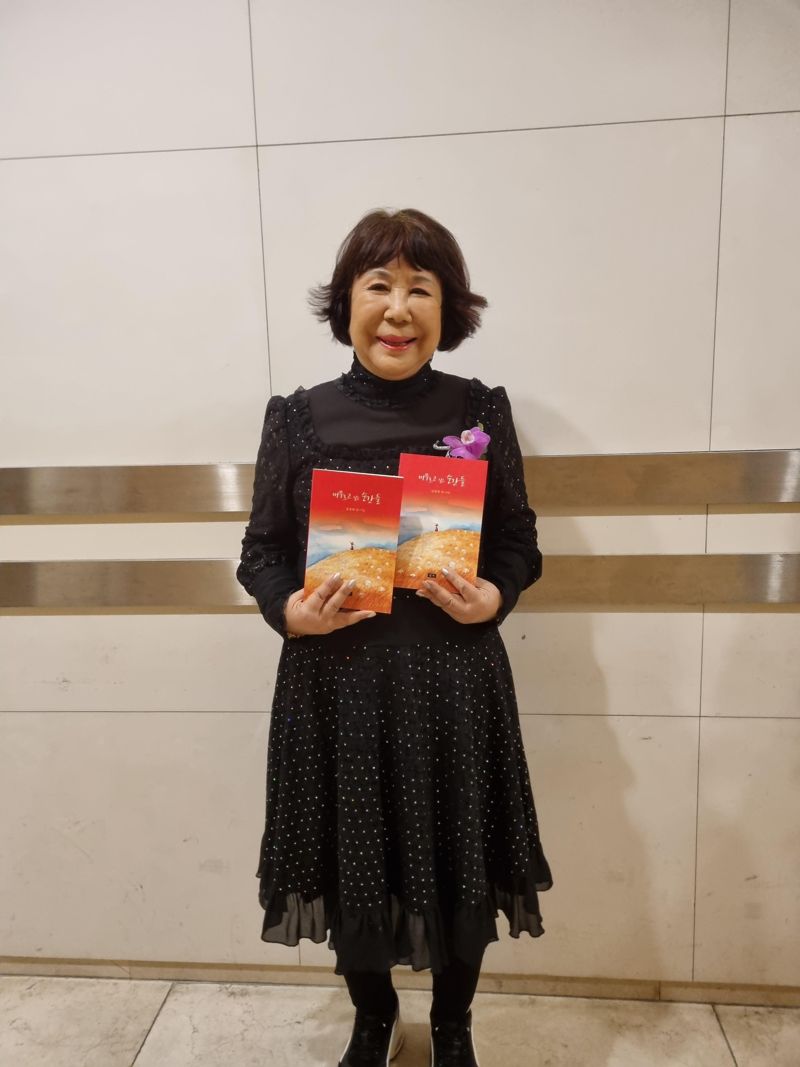 자신의 다섯 번째 시집 ‘머무르고 싶은 순간들’을 들어보이며 포즈를 취하고 있는 김경희 시인. 우진선박 제공