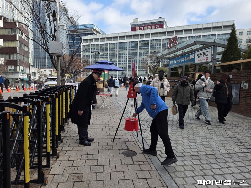 24일 오후 서울 중구 명동성당 앞에 마련된 구세군 자선냄비에 한 시민이 지폐를 넣고 있다. 사진=박성현 기자