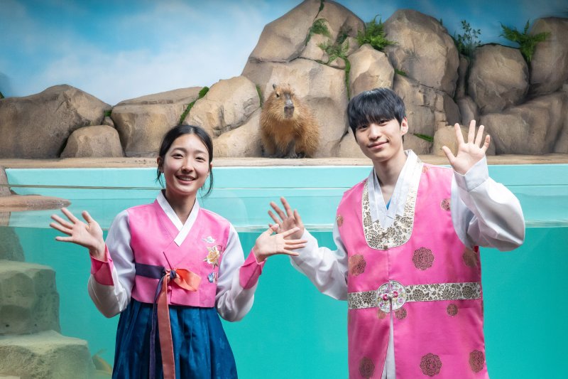 카피바라 수조 앞에서 포즈를 취하고 있는 아쿠아리스트들